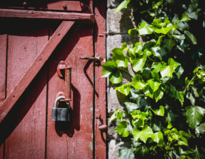 A old silver padlock on a red barn door