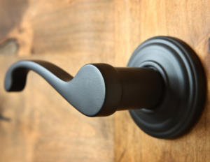 Black lever handle lock on a light wood door