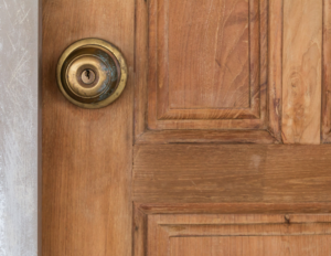 Vintage gold knob lock on a medium wood door